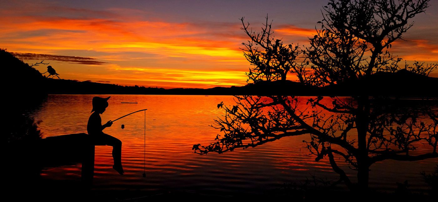child fishing at sunset